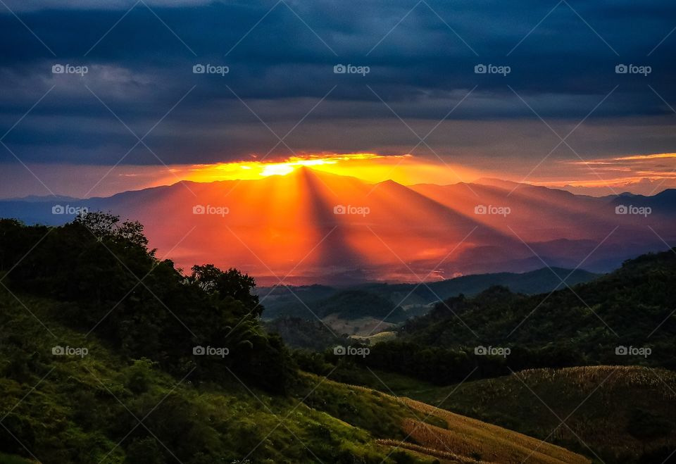 Sunburst at sunset in Nan, Thailand. The mountain and the clouds above created a small outlet for light to escape, creating this beautiful sunset.