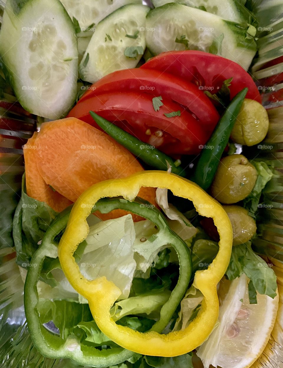 Vegetable salad close up photography, view of a vegetable salad with different colors of vegetable cuts, cucumber,yellow capsicum,tomatoes,green olives,carrots,green capsicum etc
