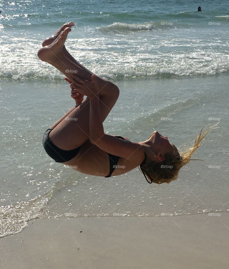 Woman backflipping at beach