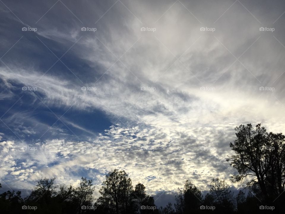 Cloud layering. Evening sky with wind swept clouds of intriguing patterns floating by