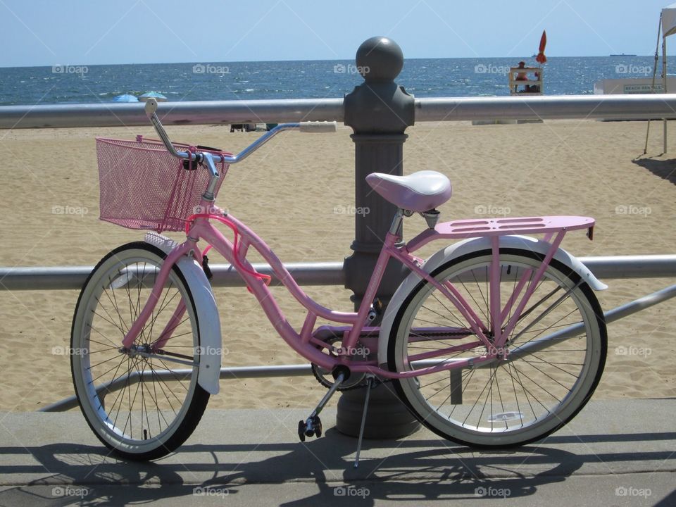 Cute pink girl’s bike on the boardwalk at the beach.