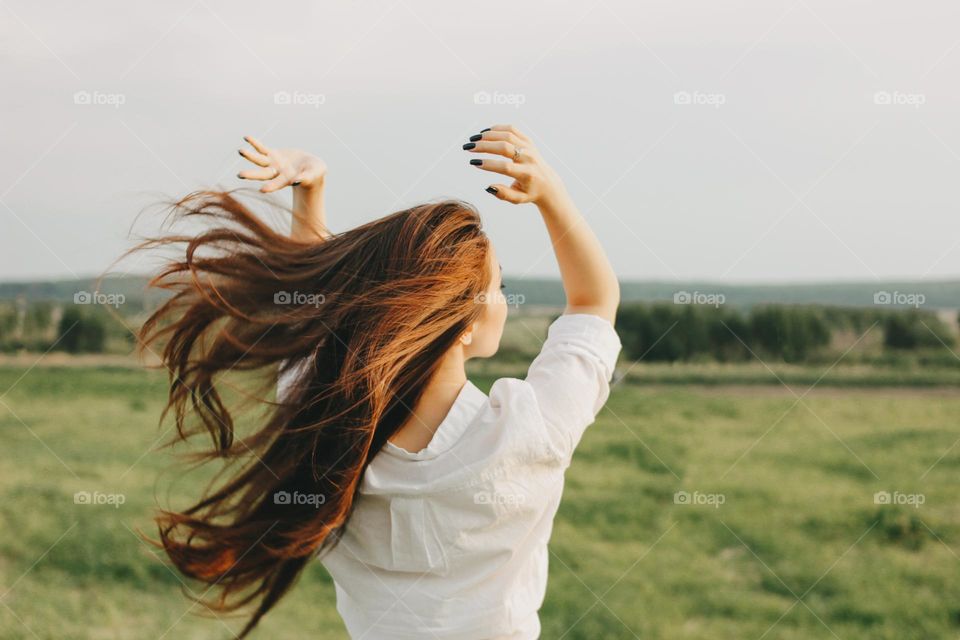 Close up portrait of beautiful carefree long hair girl in white clothes in nature field, view from back. Sensitivity to nature concept