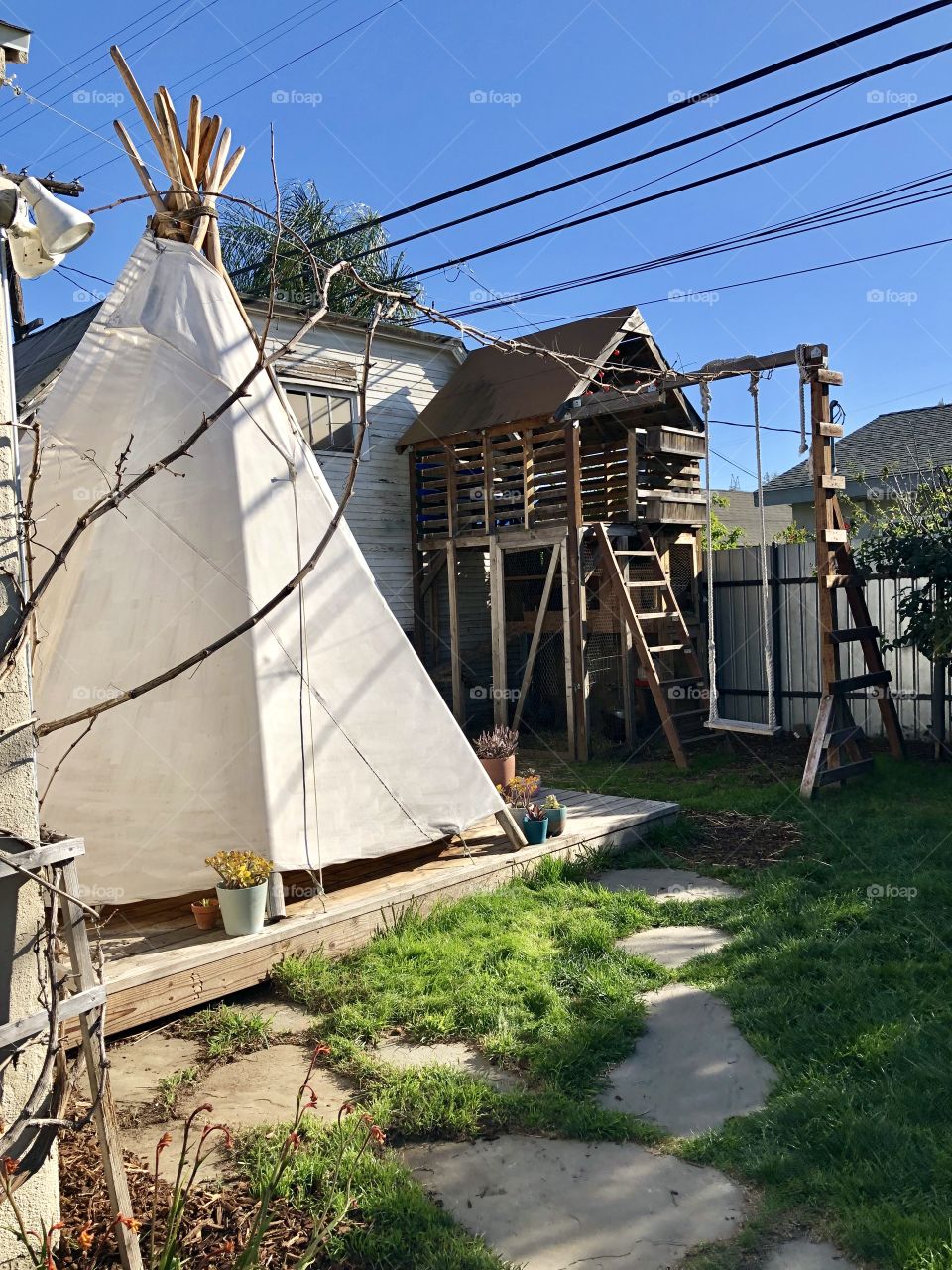 A dreamers backyard with a tee pee and swing set
