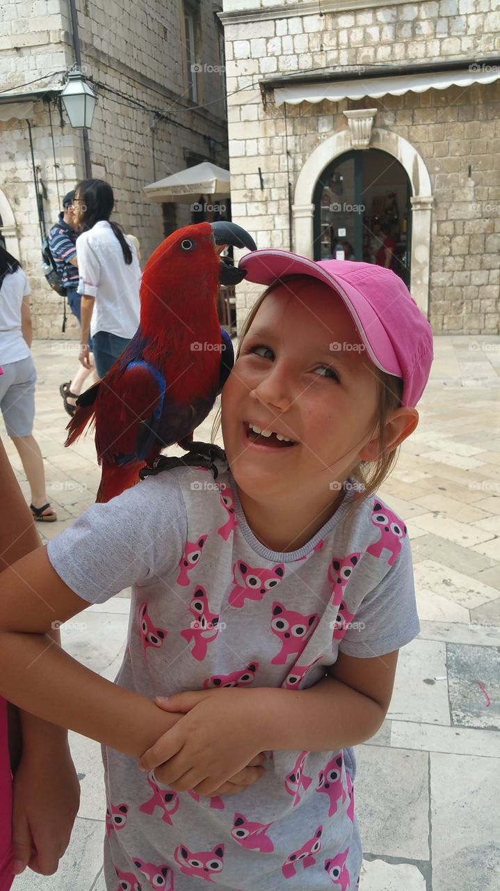 Portrait of a happy girl with red parrot