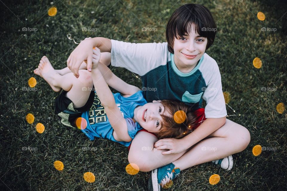 Brothers sitting on the grass laughing 