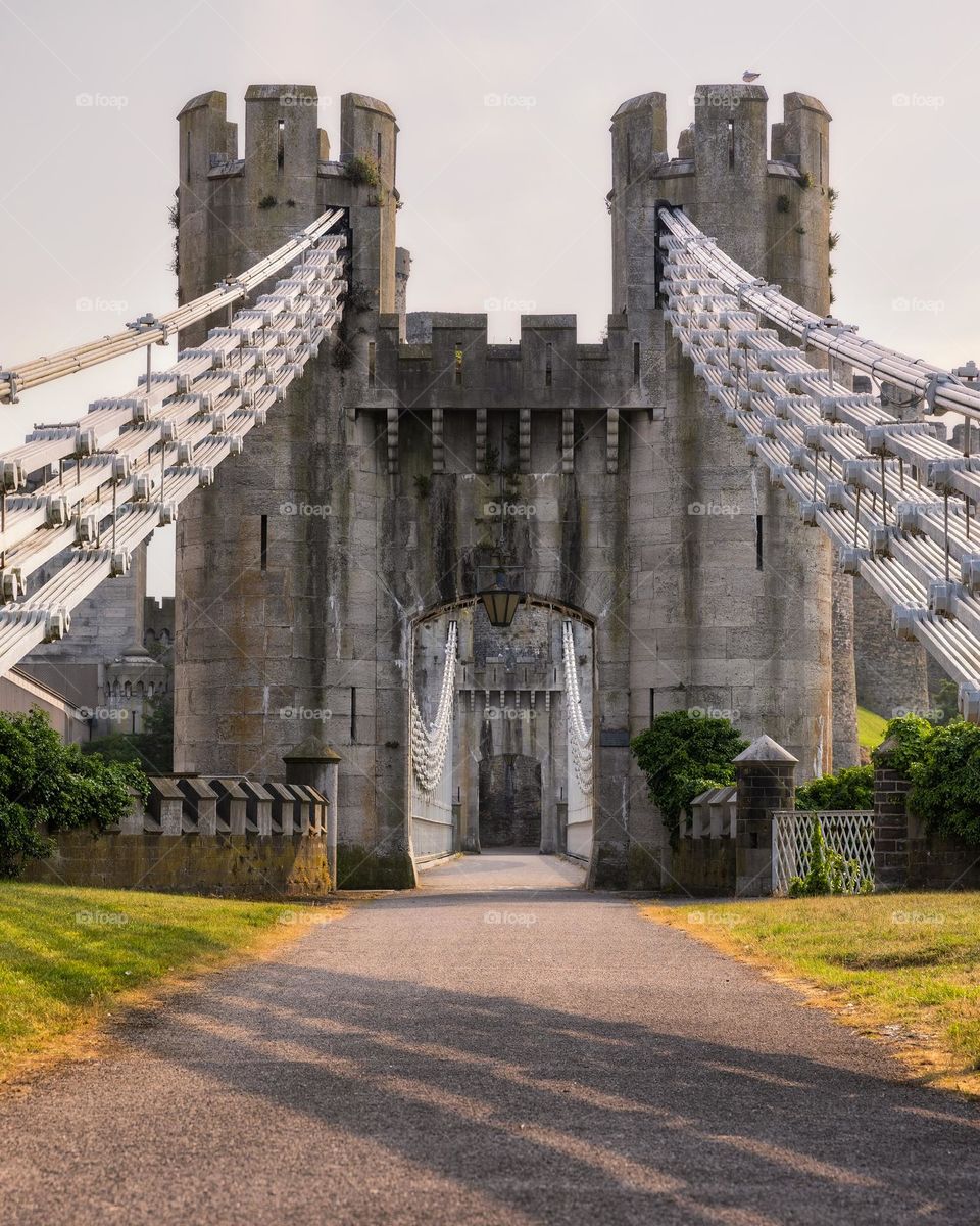 Gate entrance to an old stone castle in North Wales, Conwy Castle, with golden sunlight casting shadows as the sun sets 