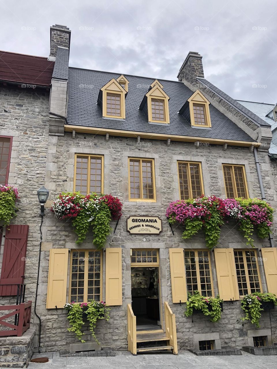 Beautiful flower arrangement at the windows painted in yellow of a stone house