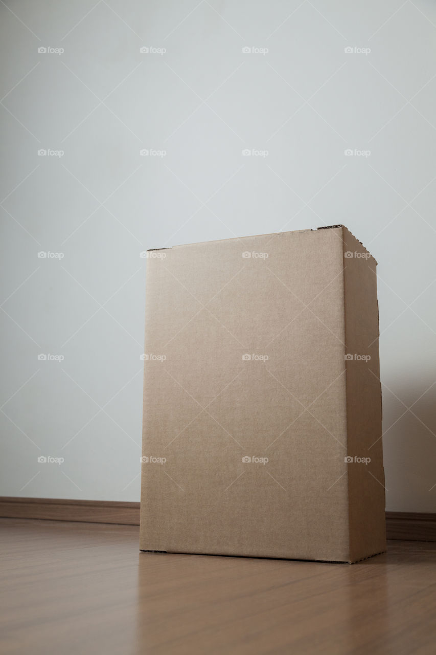 Cardboard box with order placed on the floor in an empty room with a neutral background. delivery concept. economy concept. business concept. shopping concept. copy space. Nobody