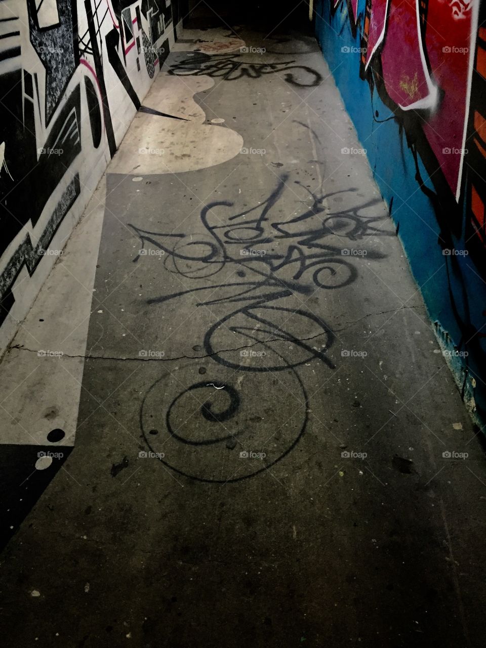 Graffiti on the floor of a hallway with an art mural in both walls