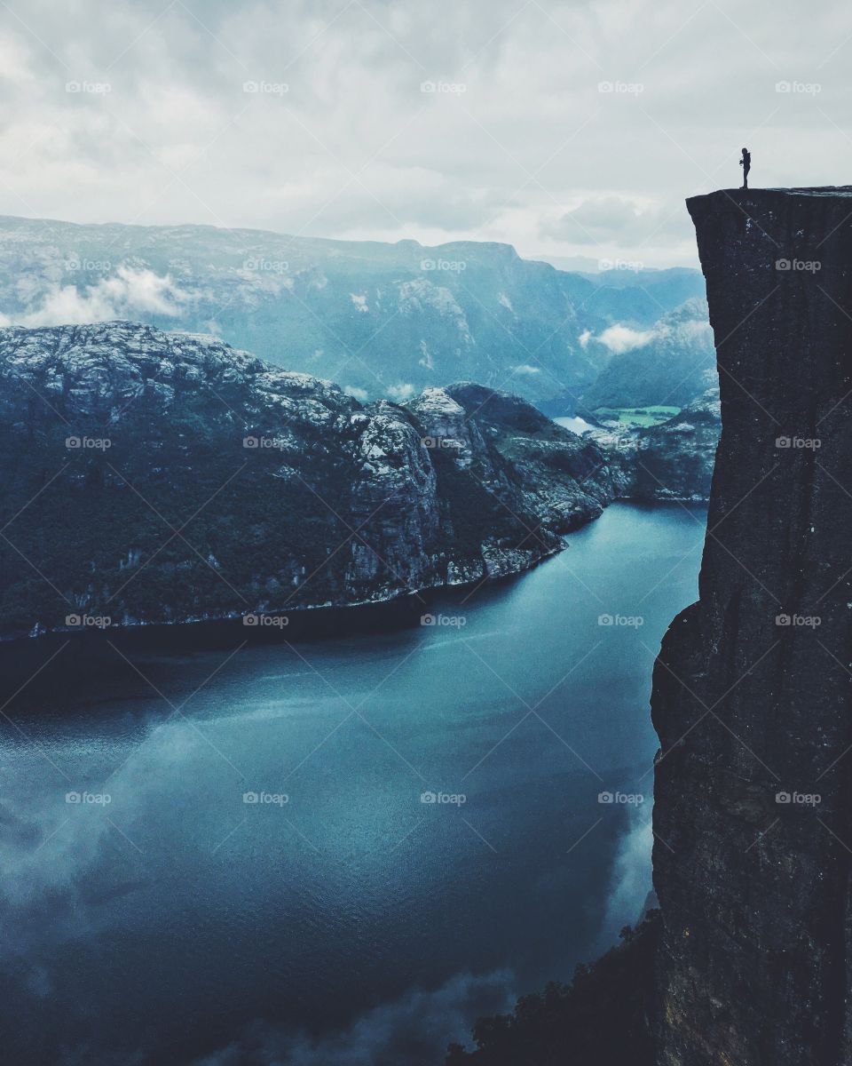 On the edge of the edge. One of my favorite places in the world. Time stops there, and it’s a meeting with pure nature. Silhouette on the edge of Prekestolen rock in Norway. 