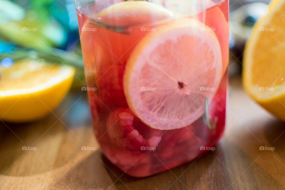 Beautiful bottle of fresh homemade juice and flavored water with raspberry and lemon on wood table with fresh ingredients conceptual healthy eating and lifestyle choices 