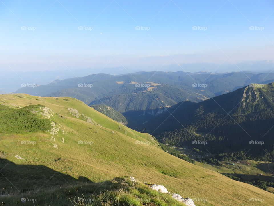 Mountain green slopes and distant mountain range