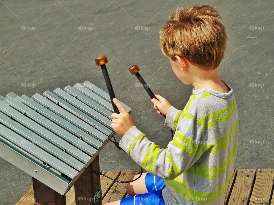 Young Street Musician. Boy Playing A Large Xylophone
