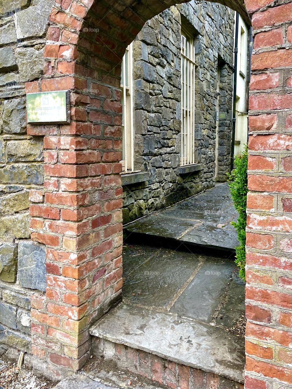 An alley lies beyond a red brick archway at the historic Bunratty Folk Park in Ireland.