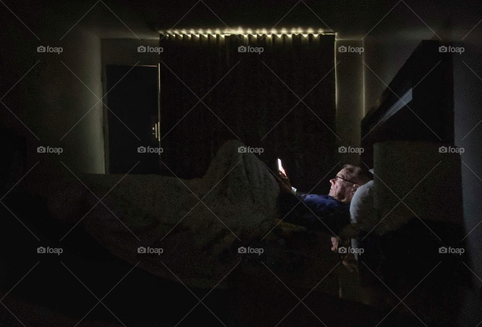 A man reading an ebook in a motel room at night