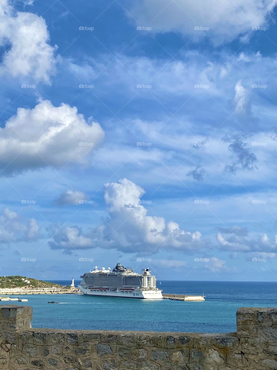 a large cruise ship in the mediterranean sea against a blue sky with white wrecks