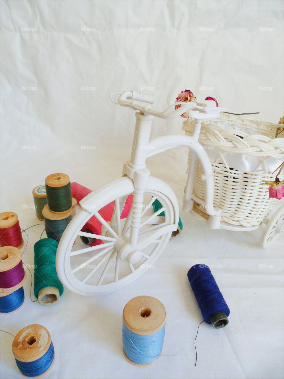 decorative toy bike, dried rosebuds and thread on white background