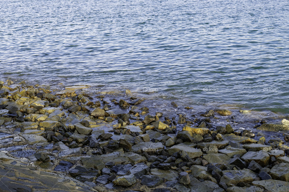 Rocks by the shore of the river. Sun light shinning on the rocks creating nice ambient.