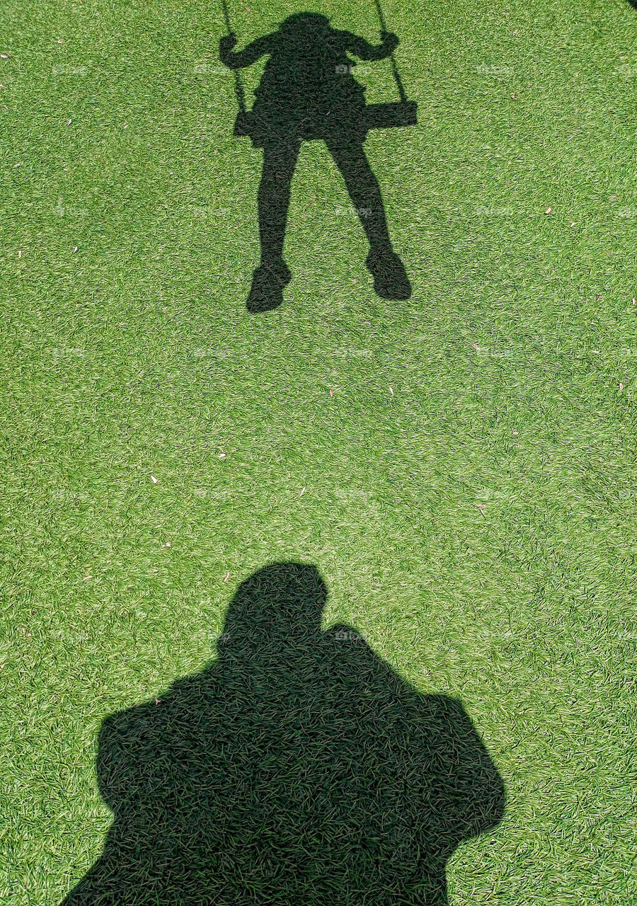 the shadow of a little girl on a swing