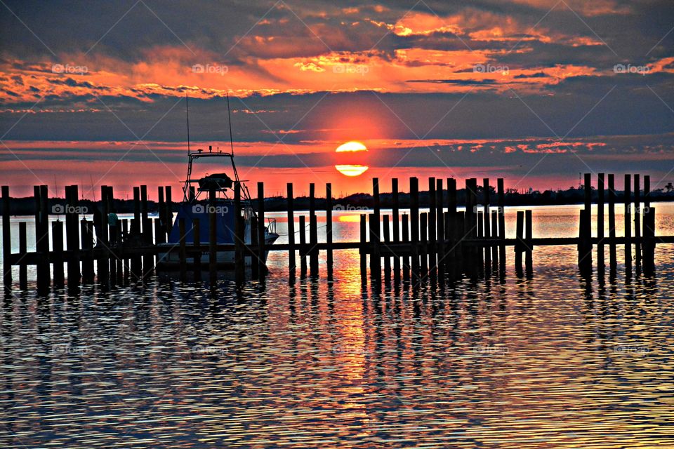 Sunrise, sunset and the moon - The brilliant sun descends behind the clouds and over the silhouetted bridge