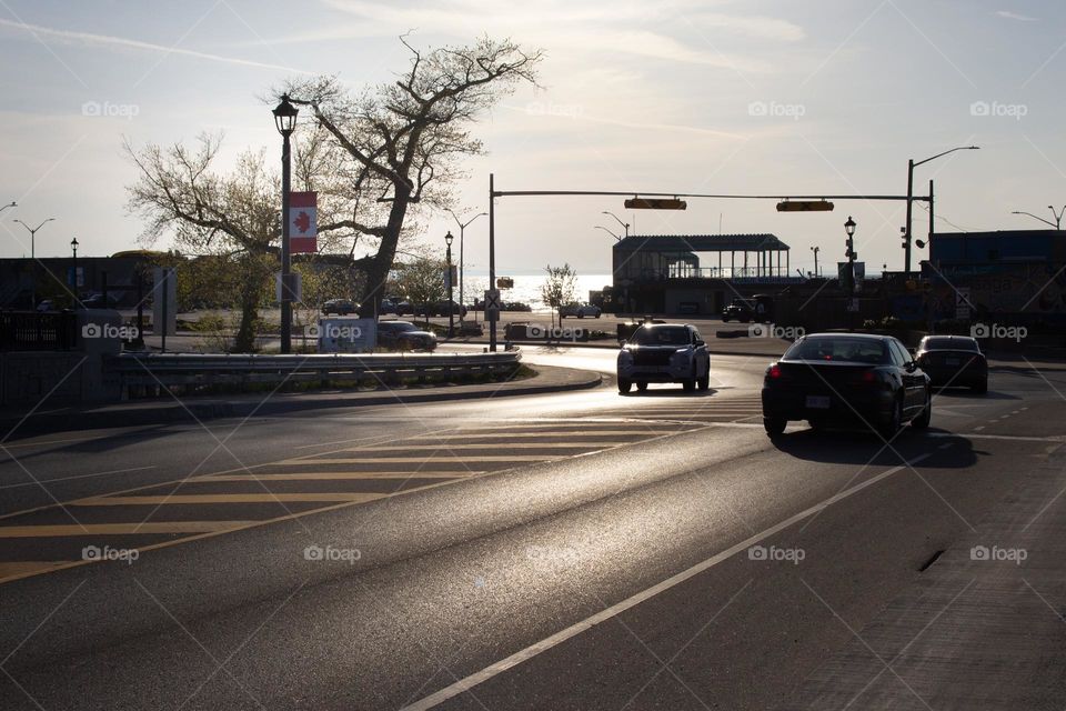 City road curving around the corner with lake view in the background and Canadian flag on a lamppost 
