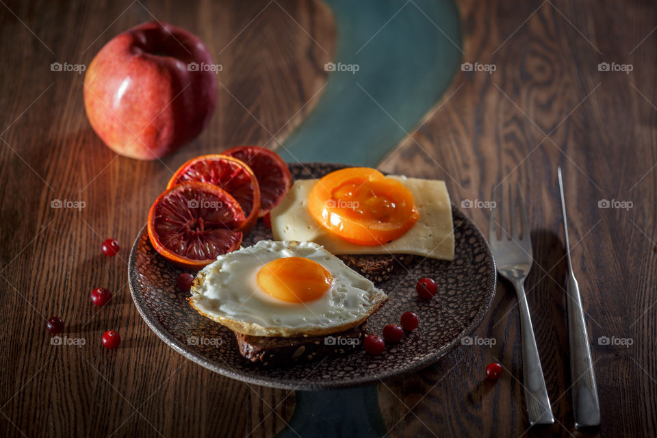 Sandwiches with fried egg orange tomato and red orange fruit 