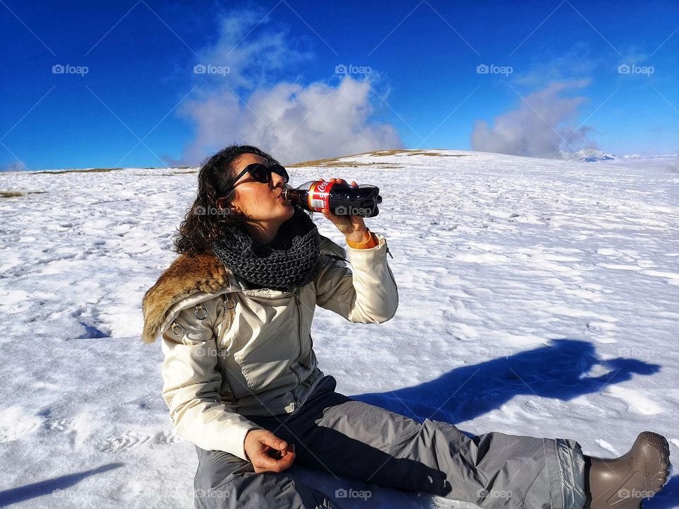 girl drinks Coca Cola sitting on the snow