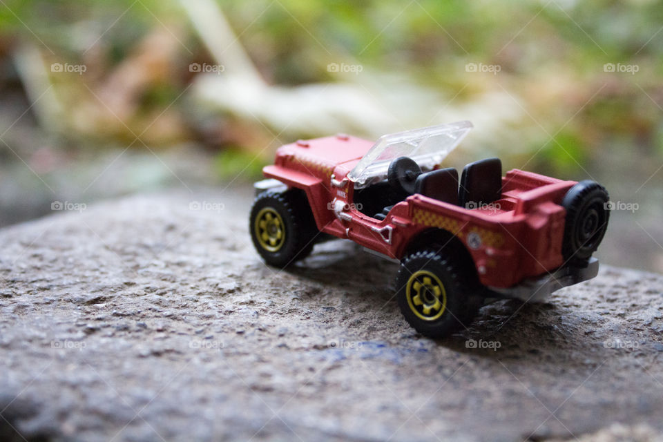 Miniature red toy Jeep on concrete with blurred background close-up macro