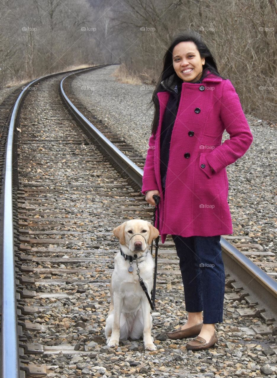 Girl standing on railroad tracks with her dog