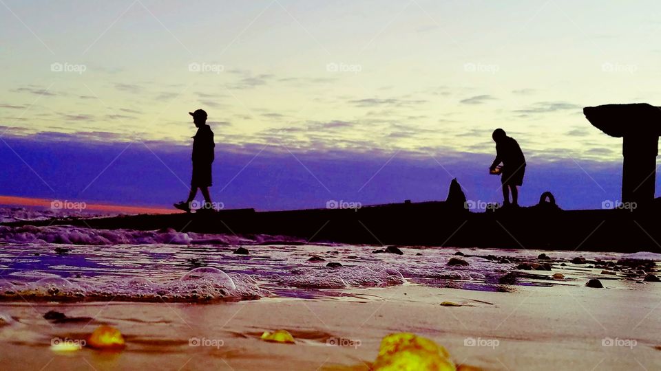 my son a boy at sunset on the beach with shells and Bubbles and sand and waves in the foreground at Bolivar peninsula Southeast Texas United States of America 2017