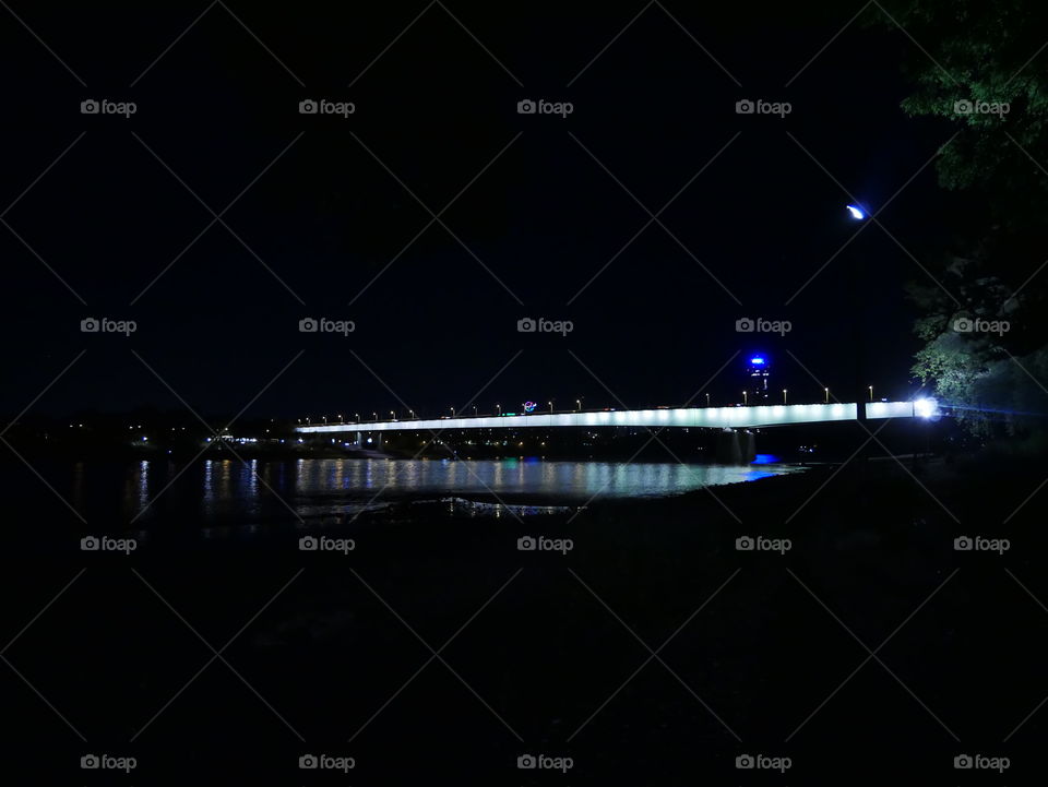 Zoobrücke vom Rheinpark bei Nacht. Mond und Stadt im Hintergrund.