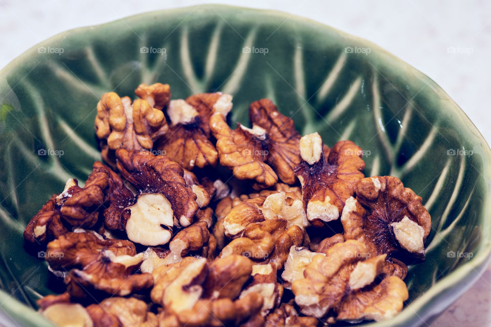 A beautiful textured green bowl full of delicious pecan nuts