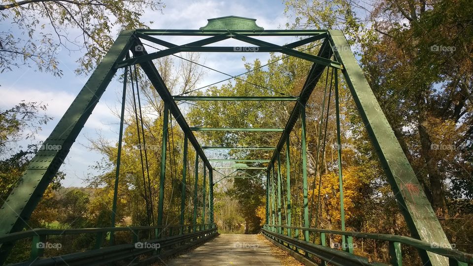 Historic old wrought iron bridge in rural Maryland spans the Cuba River in town of Butler.  Painted green with weathered rust patina and old wooden planks.  Seen here in autumn light with fall foliage.