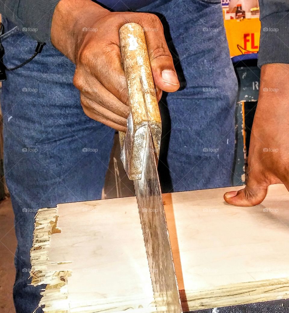 Close-up of carpenter's hand sawing wood