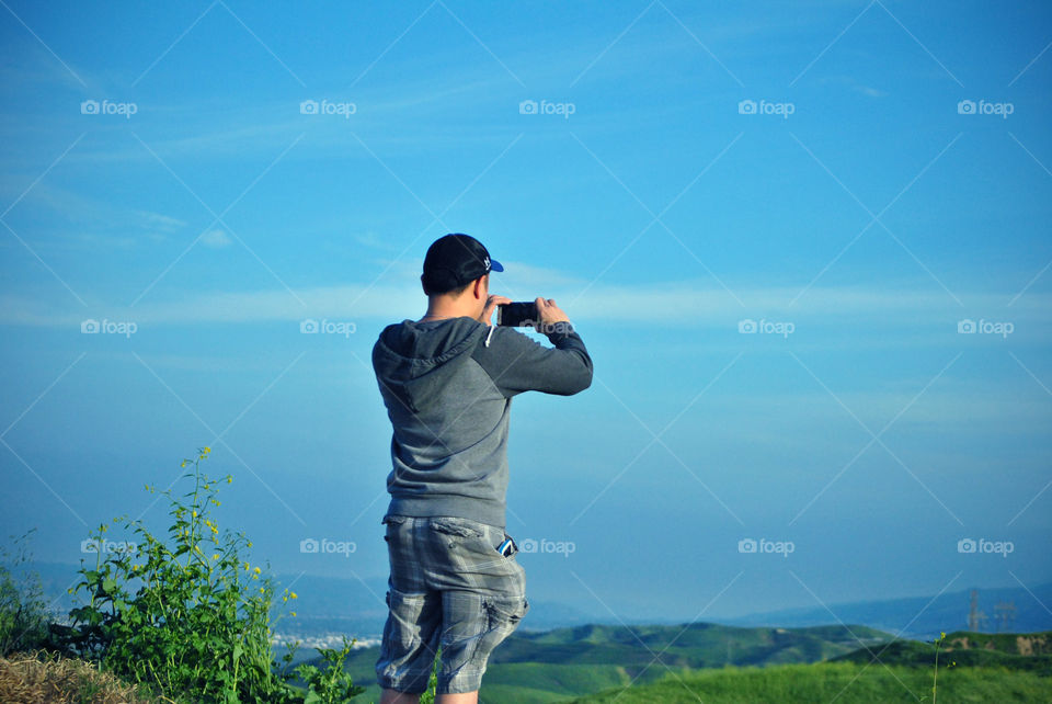 man taking a panoramic photo of the view using a mobile phone