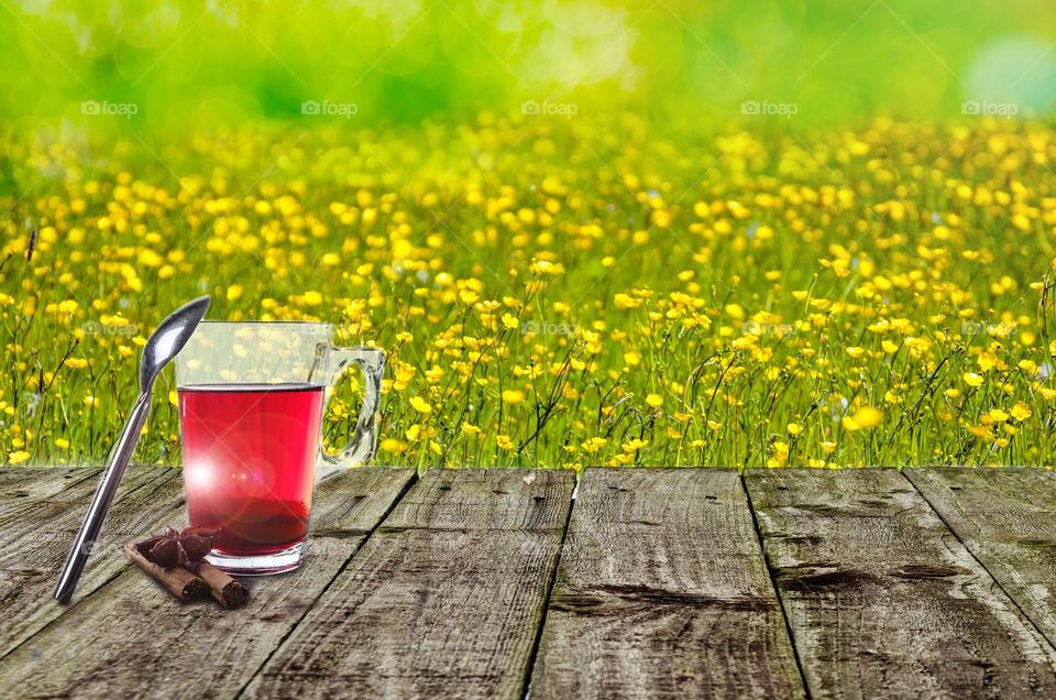 A glass of strawberry juice in the summer heat with a beautiful flowers in the background.