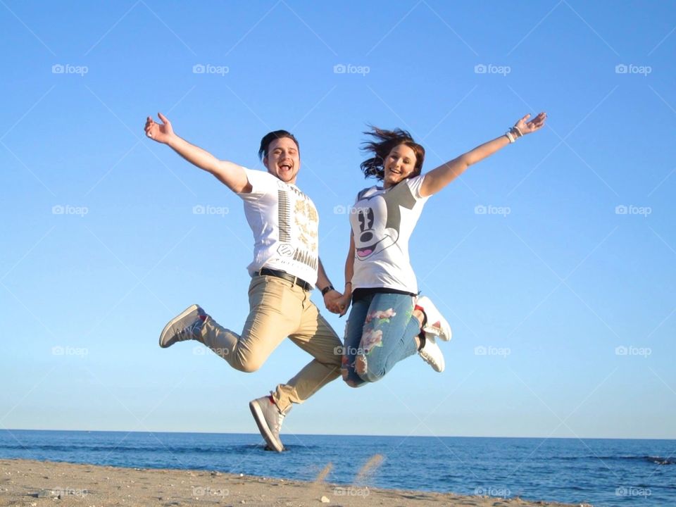 Young happy couple jumping on beach