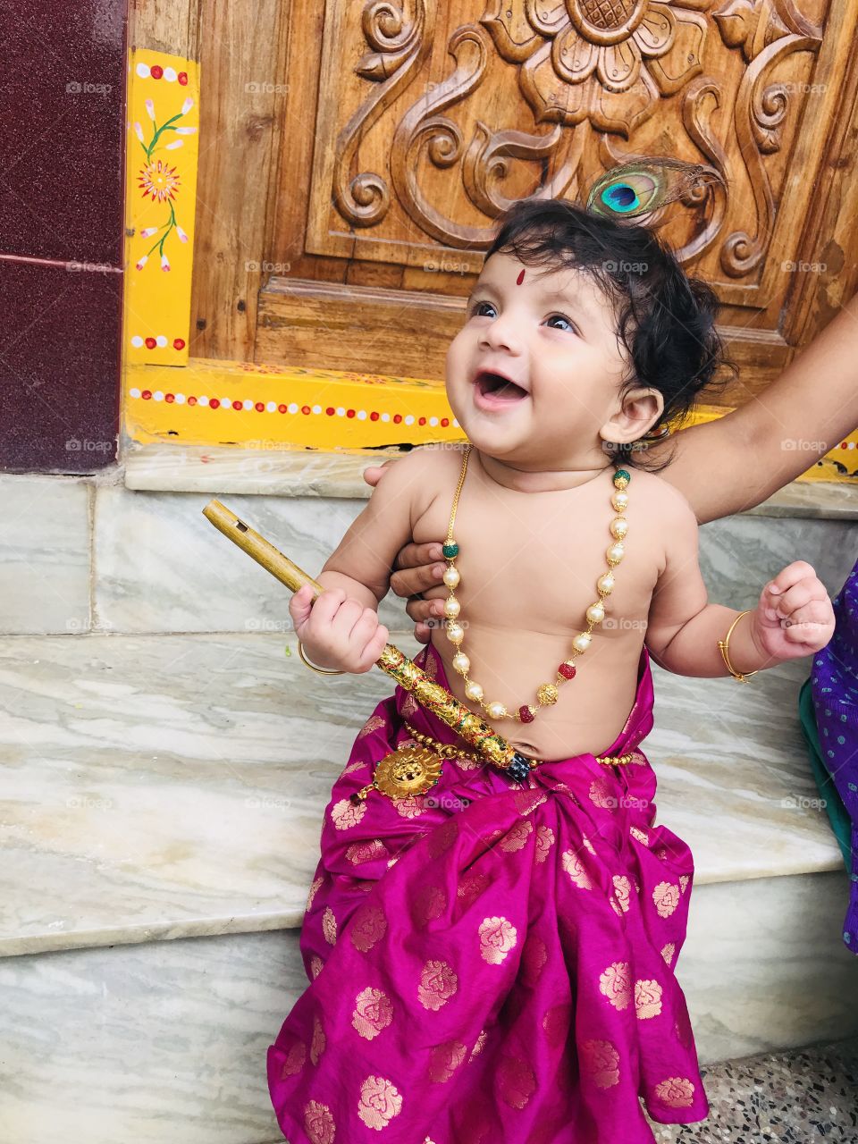 Indian baby girl dress up like Little lord Krishna and holding a flute 