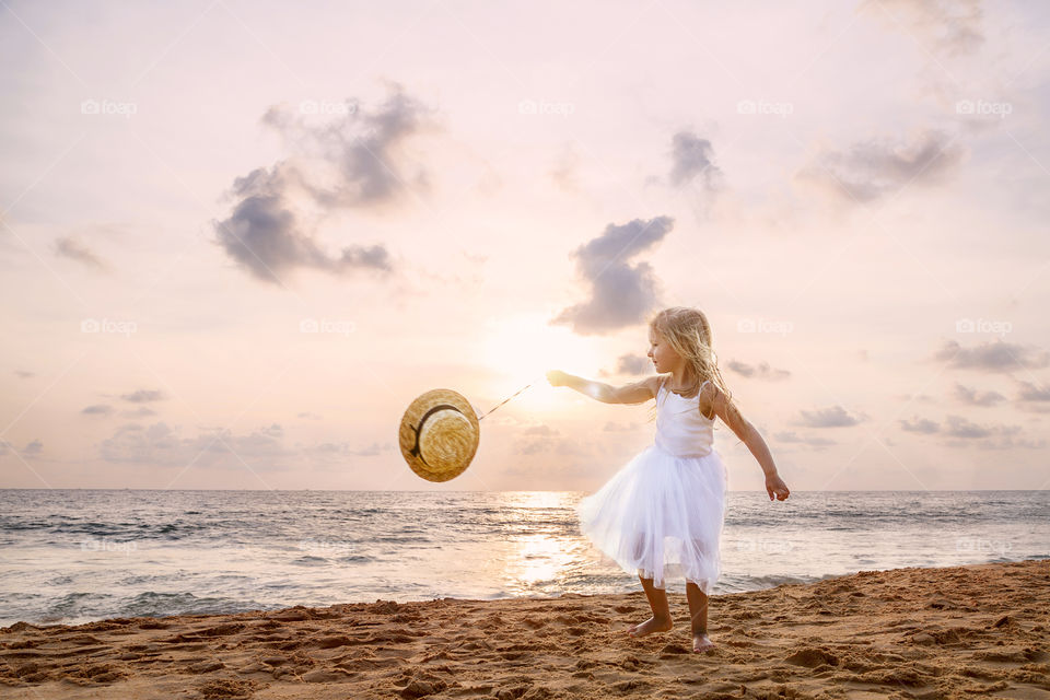 Little girl with blonde hair dancing on the beach 