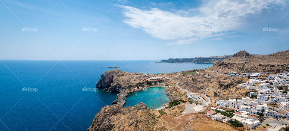 Panoramic view of enclosed St. Paul's Bay and whitewashed houses of the Lindos village, famous for its ancient Acropolis.