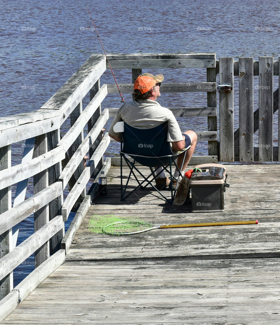 Man fishing on a dock on a sunny day