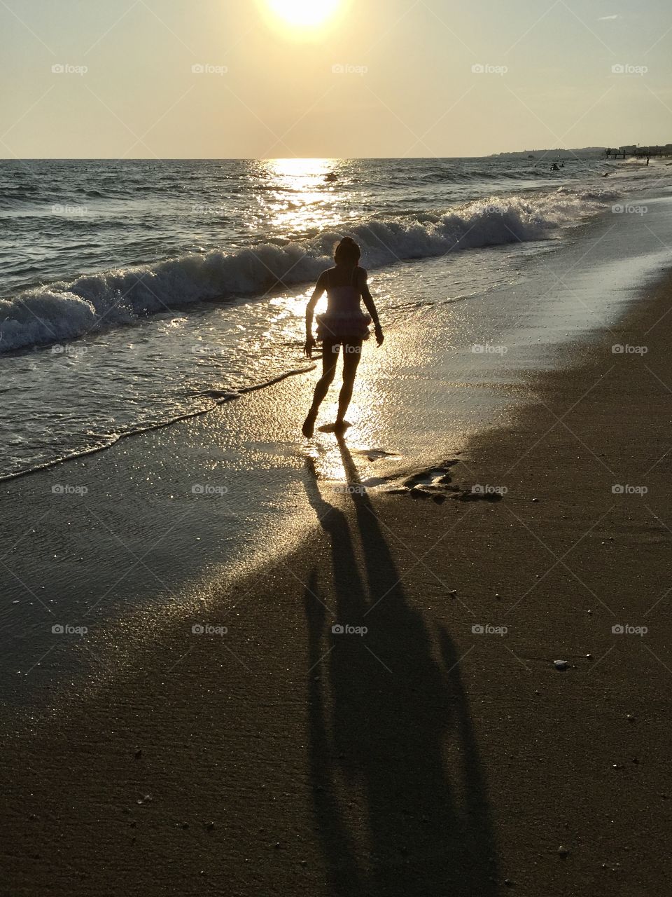a girl walks along the sea coast at sunset