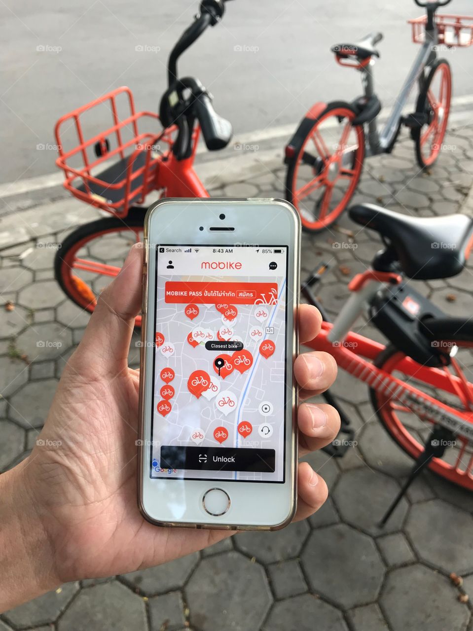 using application on iPhone for “mobike” rental bicycle which parks on footpath at public park, Chiang Mai, Thailand