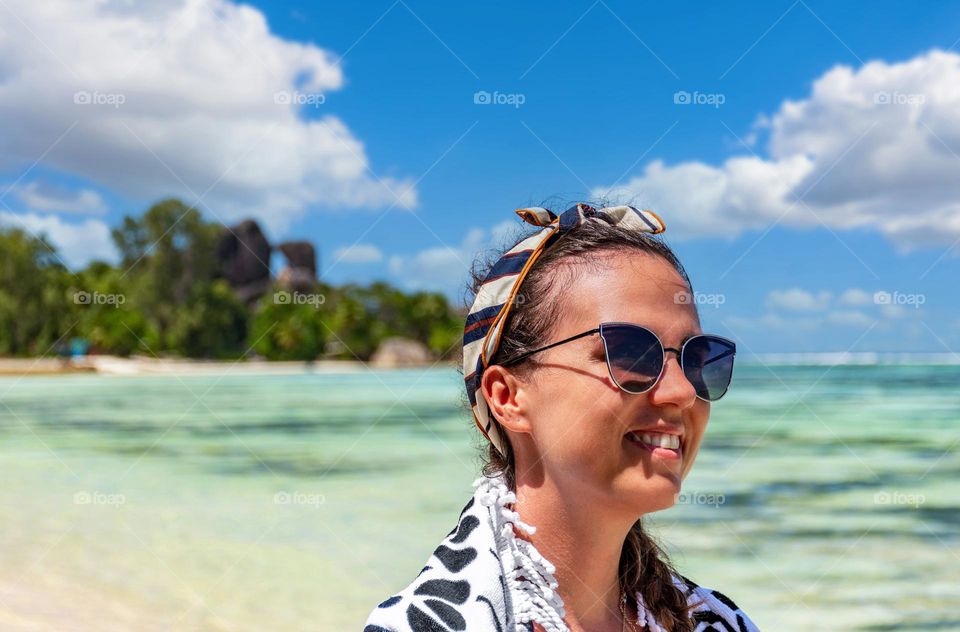 Portrait of happy young woman wering sunglasses on tropical sandy beach during summer holidays