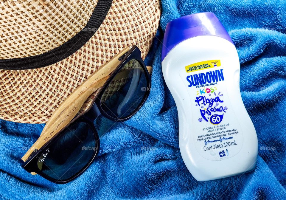 Sundown sunscreen on towel with glasses and hat. johnson and johnson product.