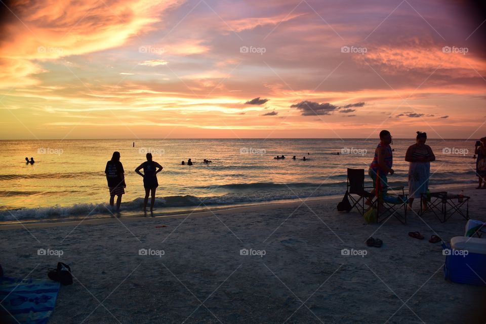 Tampa bay Floridians mull around the beach as a beautiful sunset unfolds.