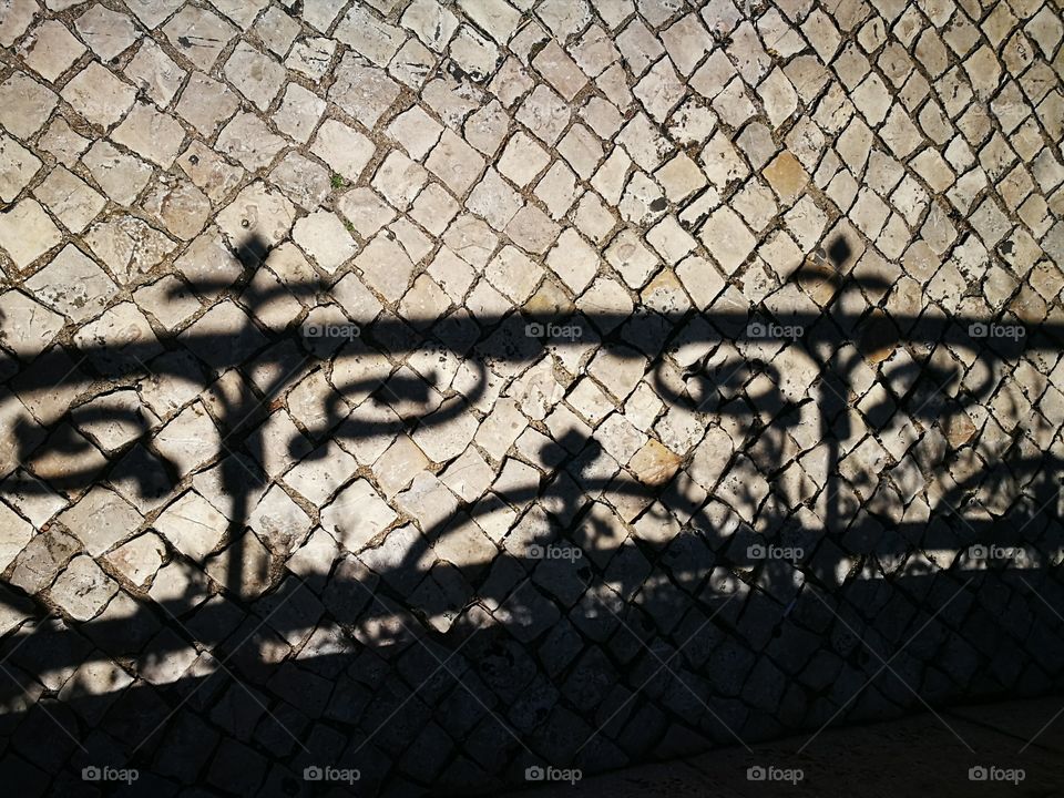 Shadows on portuguese pavement in a bright sunny day.