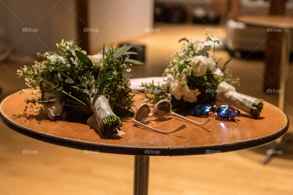 Two bouquets and two pairs of sunglasses lay forgotten on a table at the end of the night of a raucous Irish Catholic wedding on St. Patty’s day.