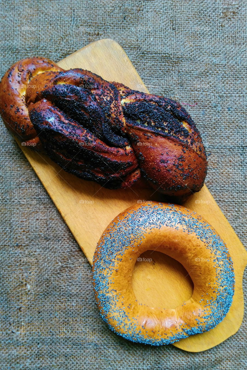 A bagel with poppy seeds and a basket with poppy seeds lie on the table