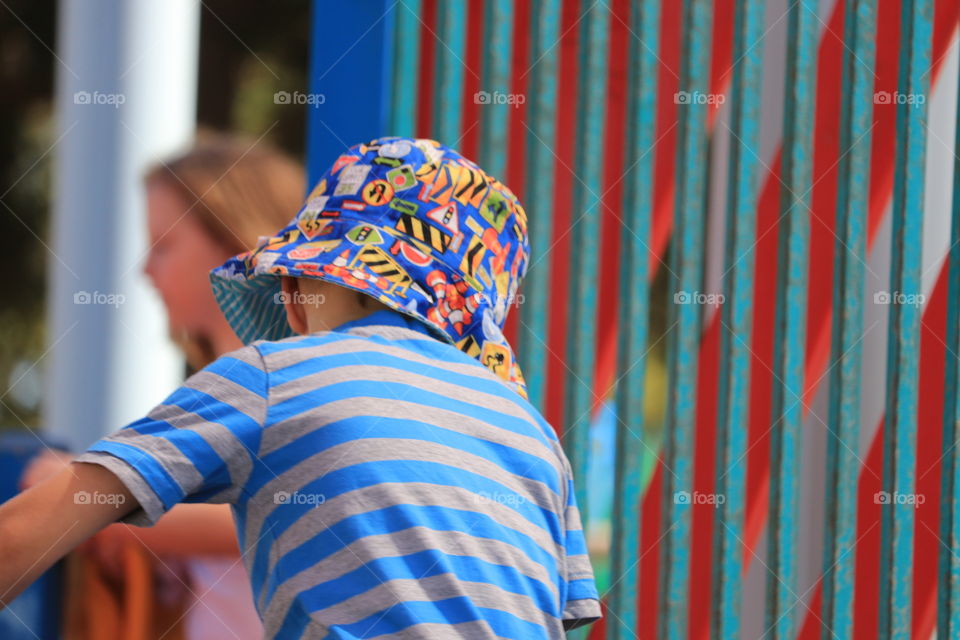 Little boy in playground play park wearing sunhat and striped shirt 